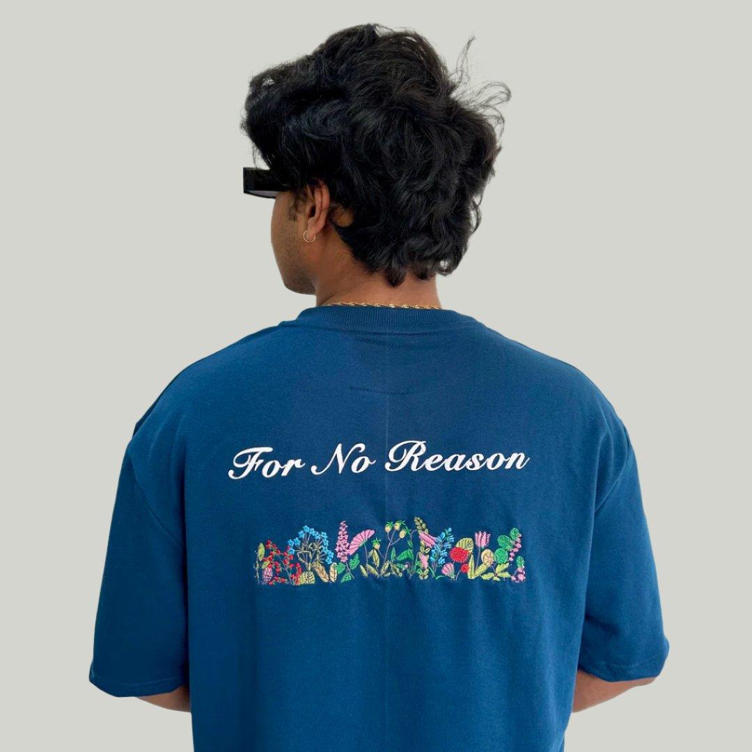 A man wearing the AIRFORCE blue FNOR t-shirt, featuring embroidered flowers and the text “For No Reason” in white puff print on the back.