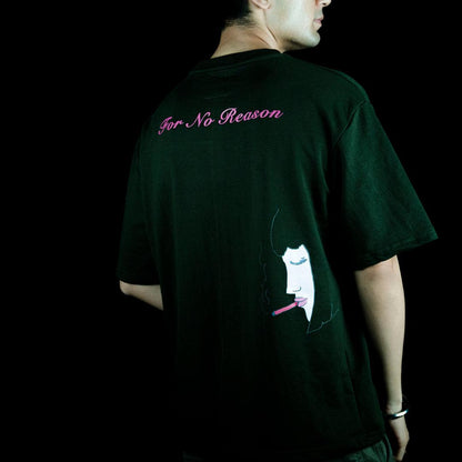 A man wearing the OG OLIVE GREEN T-SHIRT by FNOR, featuring a pink “For No Reason” puff print on the back along with a smoking face illustration.