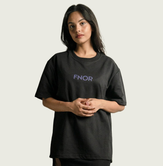 A model wearing the FNOR TWO FACE BLACK T-SHIRT, featuring the brand logo in purple on the front, showcasing the minimalist design from the FNOR Minimalist Series.